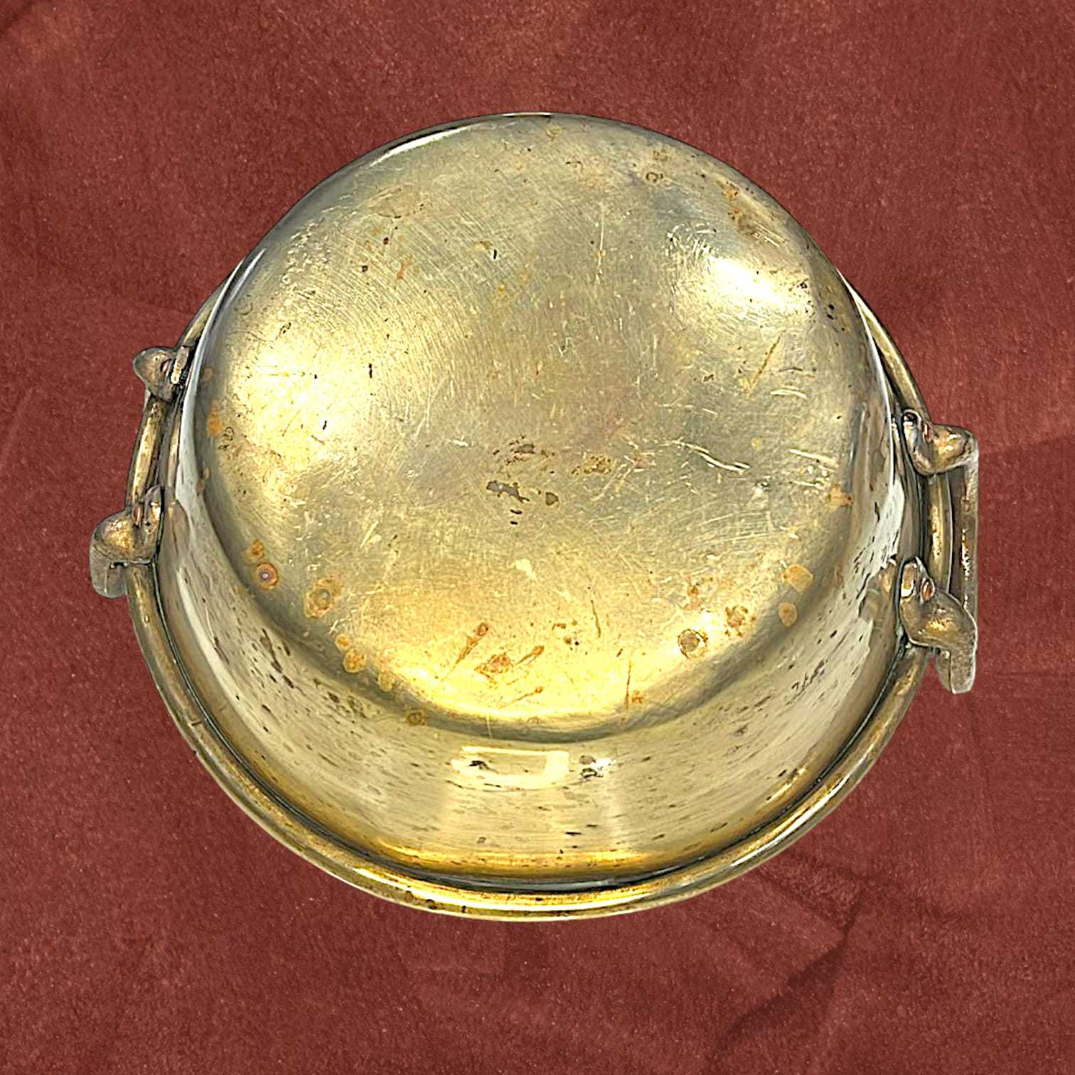 Base del caldero de metal antiguo dorado, muestra su estructura sólida y envejecida. Ideal para decoración de estilo retro o artesanal.