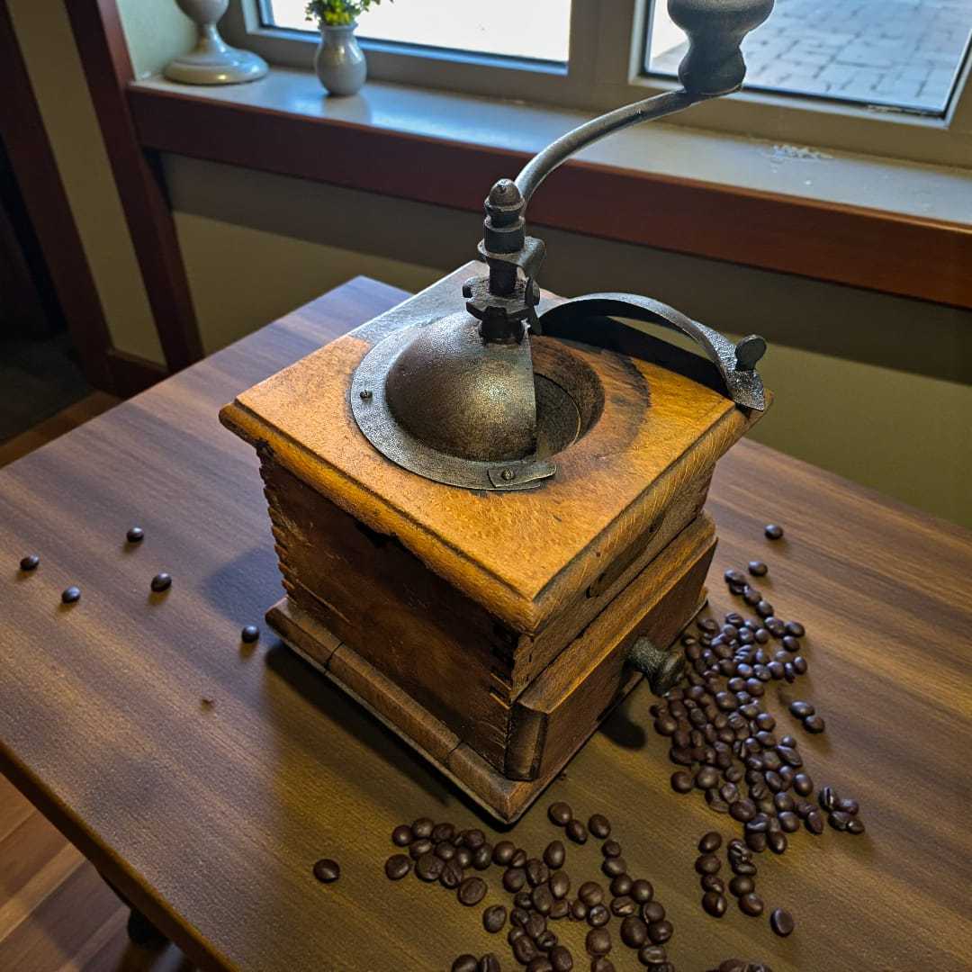 Molinillo de café antiguo manual Elma de madera sobre mesa con granos de café en cafetería. Decoración vintage ideal para coleccionistas.