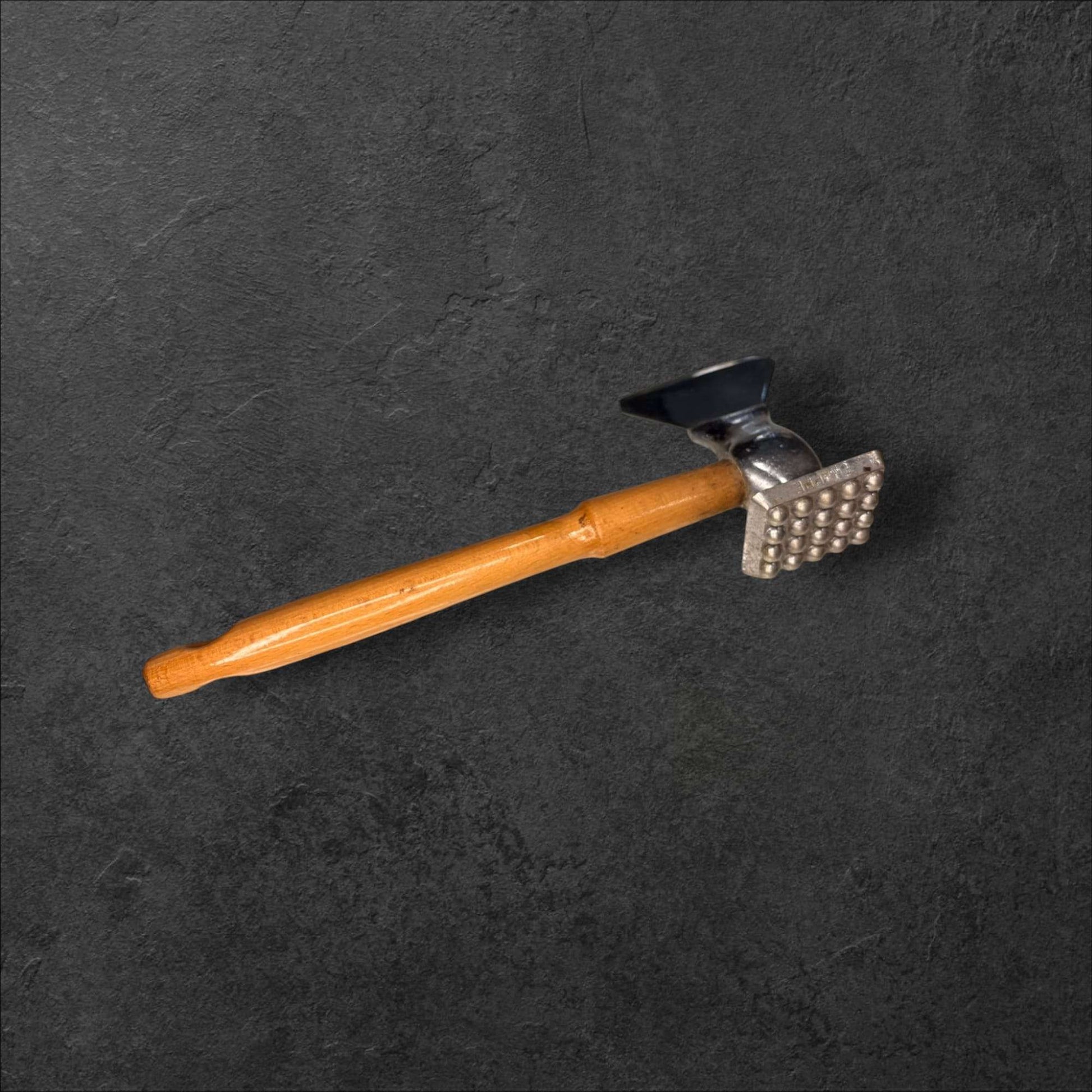 Perspectiva trasera del martillo de carne antiguo con superficie texturizada, pieza decorativa única para hogar o jardín estilo rústico.