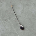 Cuchara de cóctel de metal plateado vintage con mango largo y espiral, ideal para decoración de bar en estilo retro elegante.
