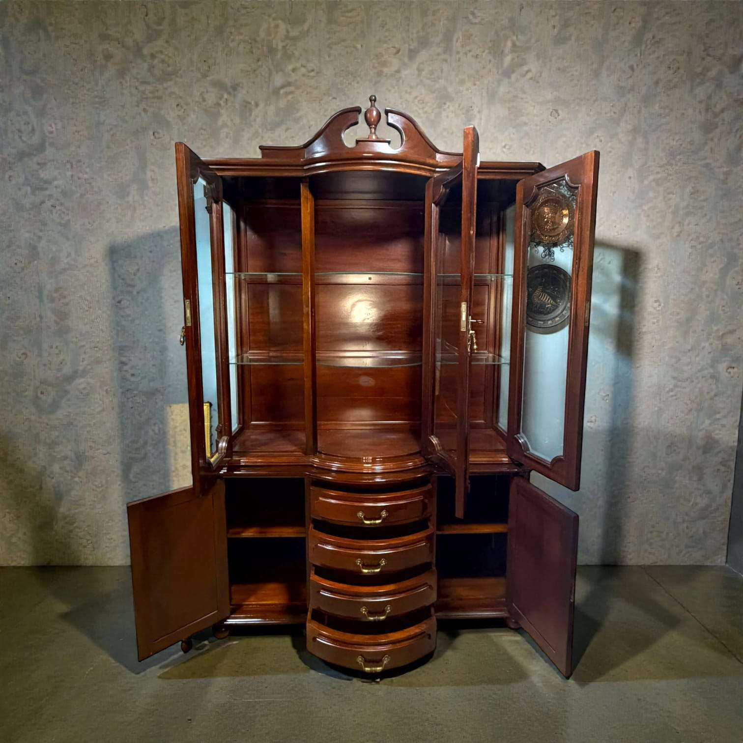 Vitrina de caoba clásica antigua con cristales biselados, puertas abiertas, cajones centrales y estantes de vidrio. Ideal para decoración de salón elegante.