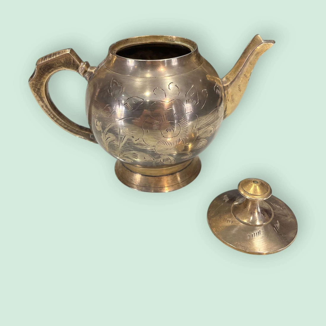 Tetera de metal dorado antigua grabada y decorativa con diseño floral, ideal para decoración vintage en el hogar o colección de antigüedades.