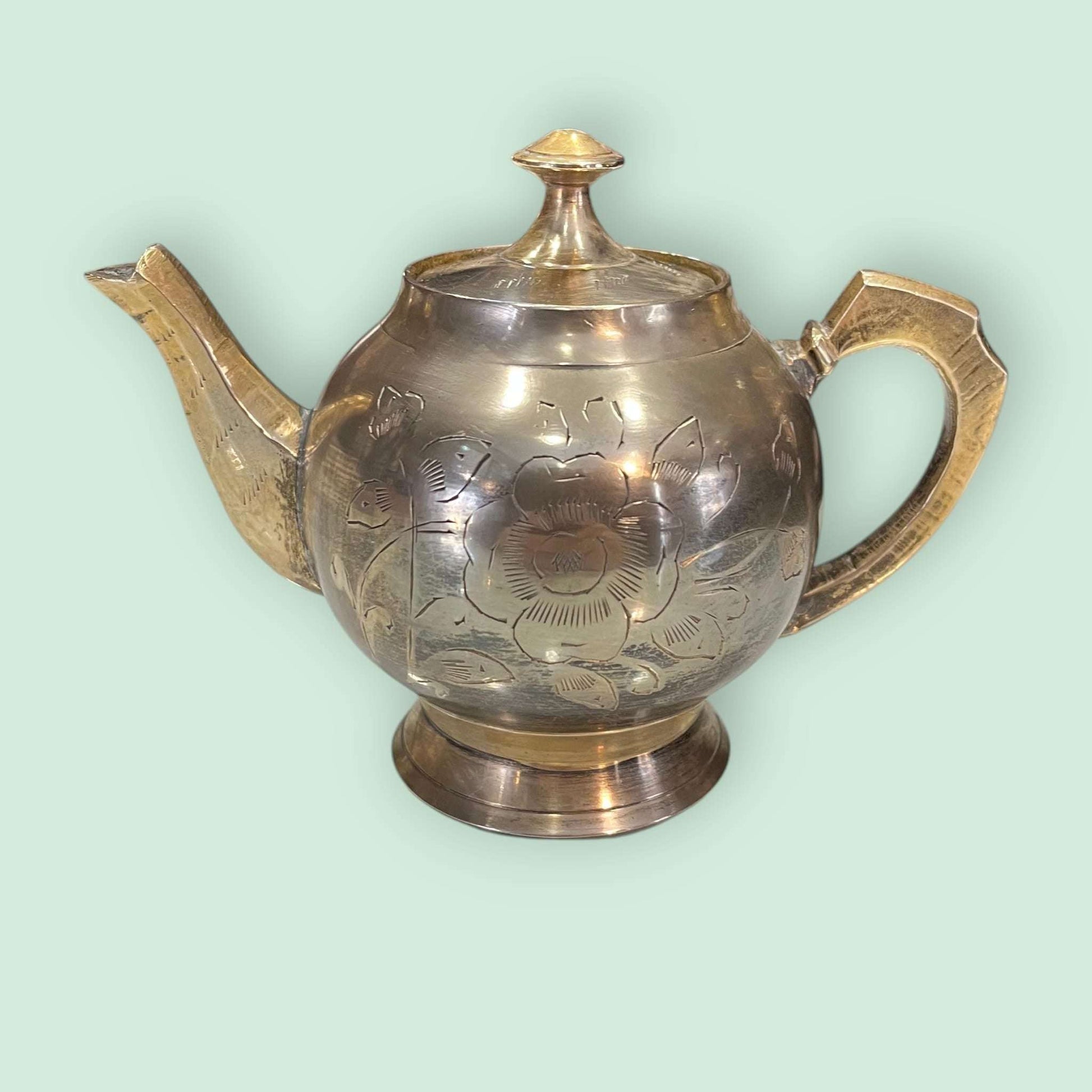 Tetera de metal dorado antigua grabada y decorativa con diseño floral, ideal para decoración vintage en el hogar o colección de antigüedades.