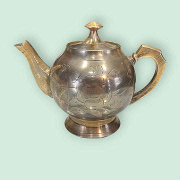 Tetera de metal dorado antigua grabada y decorativa con diseño floral, ideal para decoración vintage en el hogar o colección de antigüedades.