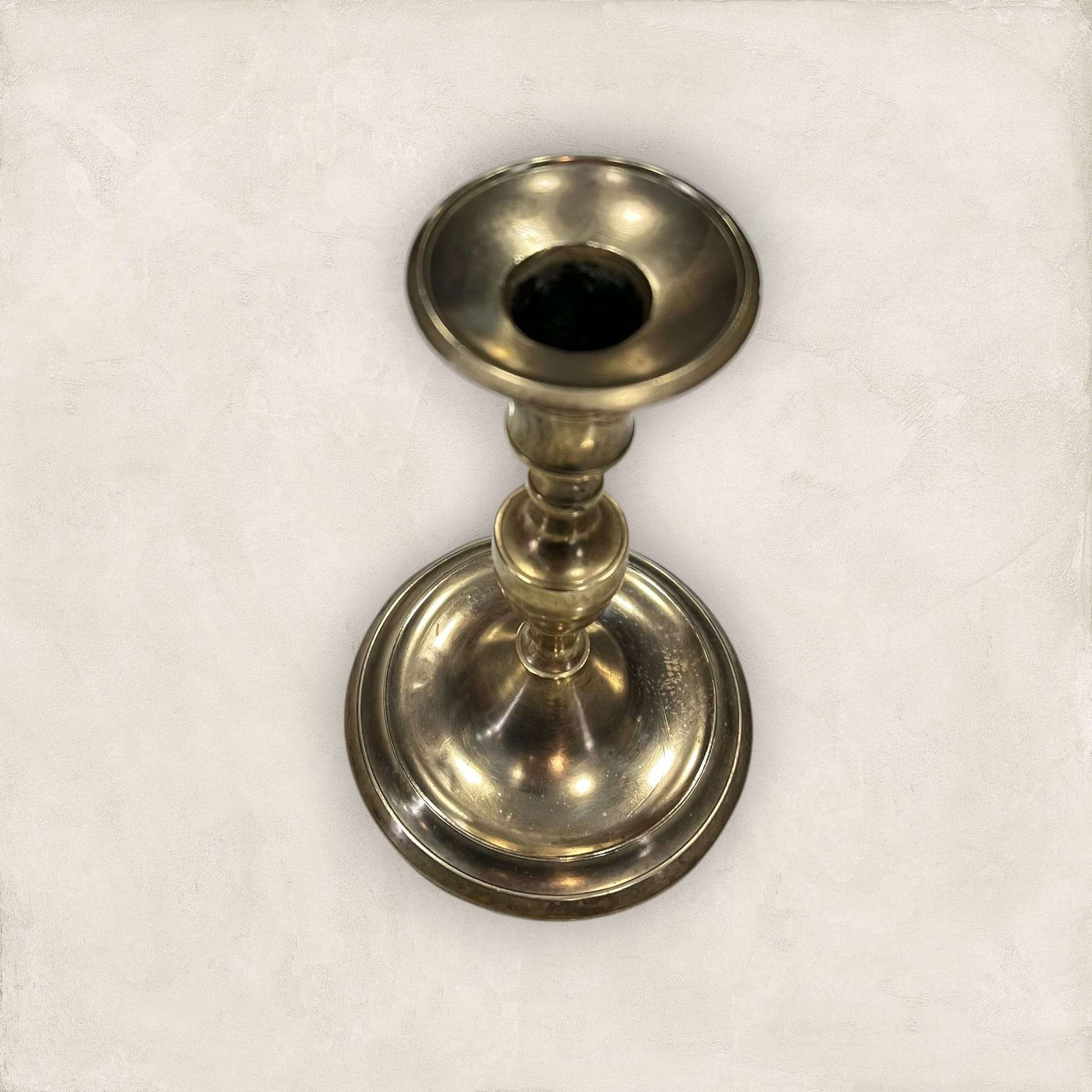 Candelabro de metal dorado con base ancha y forma torneada, ideal para velas decorativas en ambientes clásicos o coleccionismo.