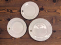 Tres platos de porcelana Royal George V con relieves y filo dorado sobre mesa de madera, ideales para mesa de gala o colección decorativa.