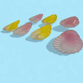 Conchas de cristal decorativas en tonos rosa y amarillo con acabado brillante, perfectas para decoración del hogar y estilo retro elegante.