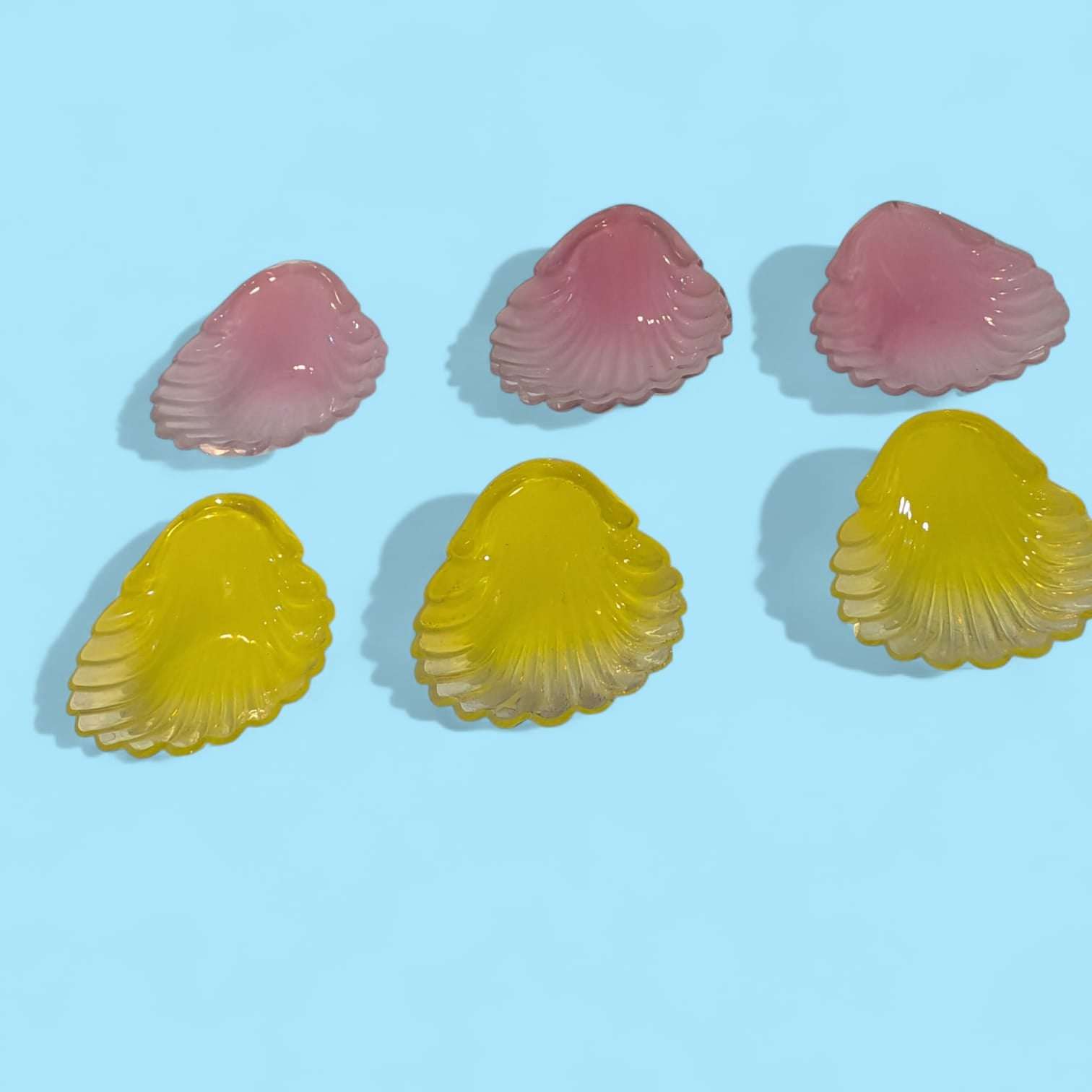 Conchas de cristal antiguas en tonos vibrantes rosa y amarillo, perfectas para colecciones decorativas y ambientaciones elegantes en el hogar.