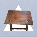 Vista superior de la mesa auxiliar Castellana de madera maciza con remaches metálicos. Pieza decorativa única para el hogar.