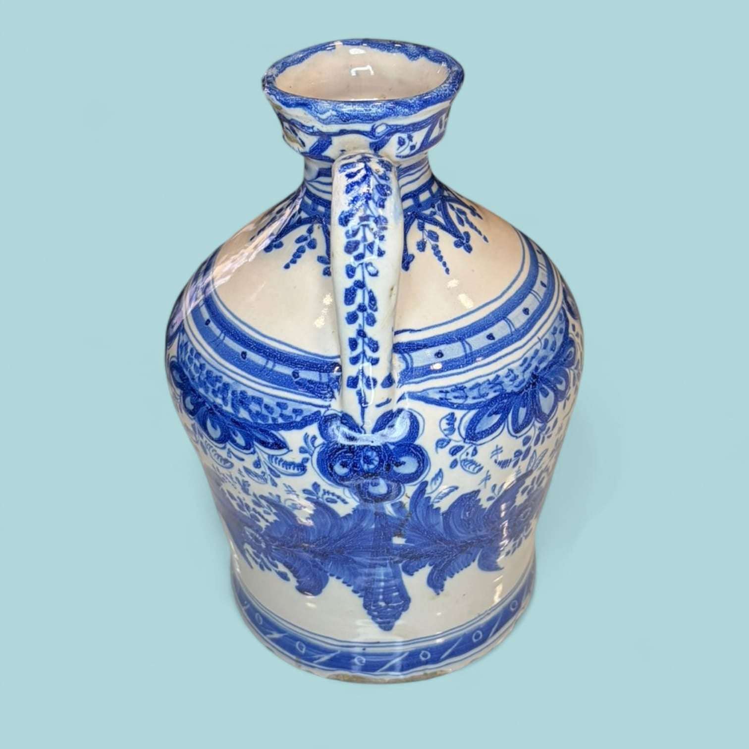 Ánfora de cerámica esmaltada azul con detalles pintados a mano y forma tradicional. Pieza decorativa única para ambientes elegantes y rústicos.