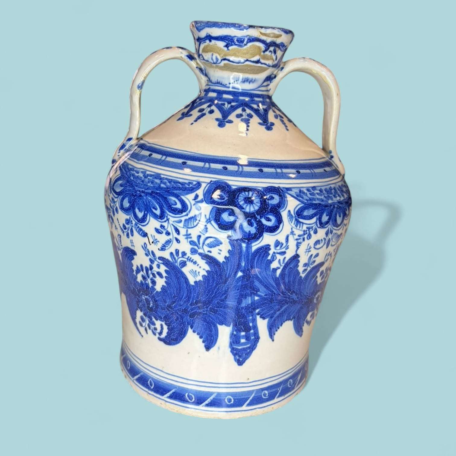 Ánfora de cerámica esmaltada azul con motivos clásicos y acabado brillante. Ideal para decoración de tejados o espacios con estilo tradicional.