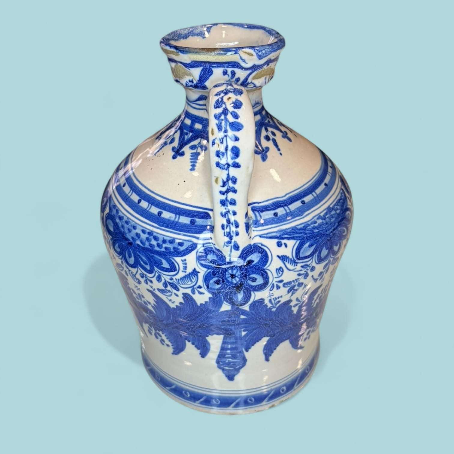 Ánfora de cerámica azul esmaltada con diseño floral simétrico y acabado artesanal. Ideal para decoración de tejado o interiores clásicos.