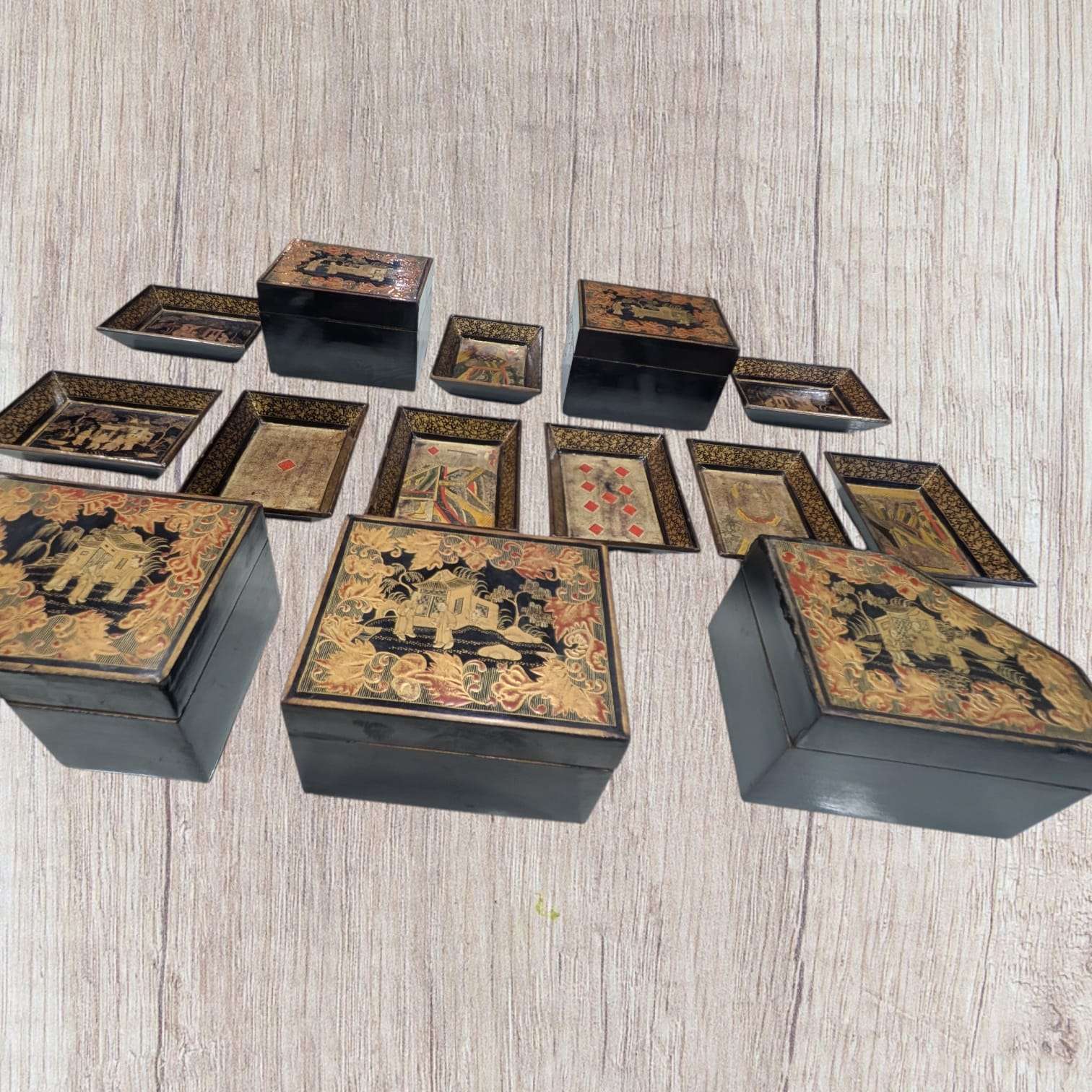 Vista en ángulo del lote de cajas y bandejas chinas Dinastía Qing, destacando su diseño artesanal en madera lacada. Ideal para decoración temática oriental.