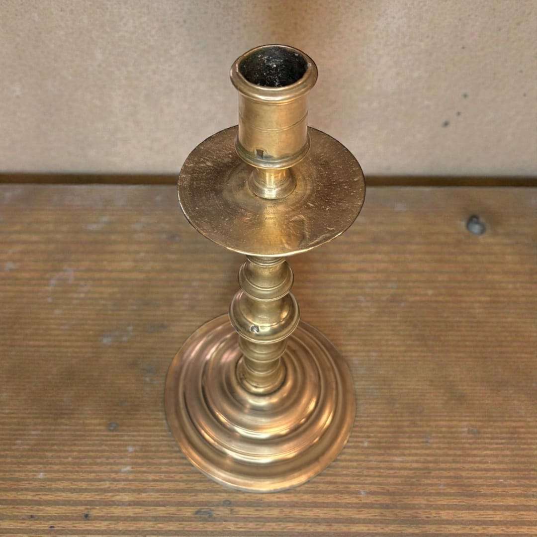 Candelabro antiguo de metal dorado para luz tradicional sobre mesa de madera, ideal para decoración clásica en interiores rústicos.