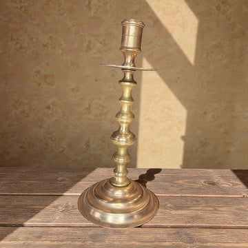 Candelabro antiguo de metal dorado para luz tradicional sobre mesa de madera, ideal para decoración clásica en interiores rústicos.