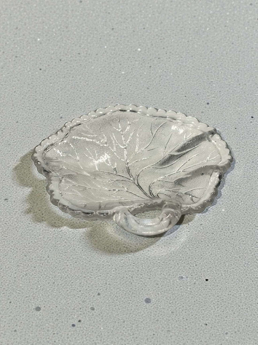 Elegante plato de cristal con diseño natural de hoja y asa integrada, perteneciente al lote de platos antiguos decorativos.