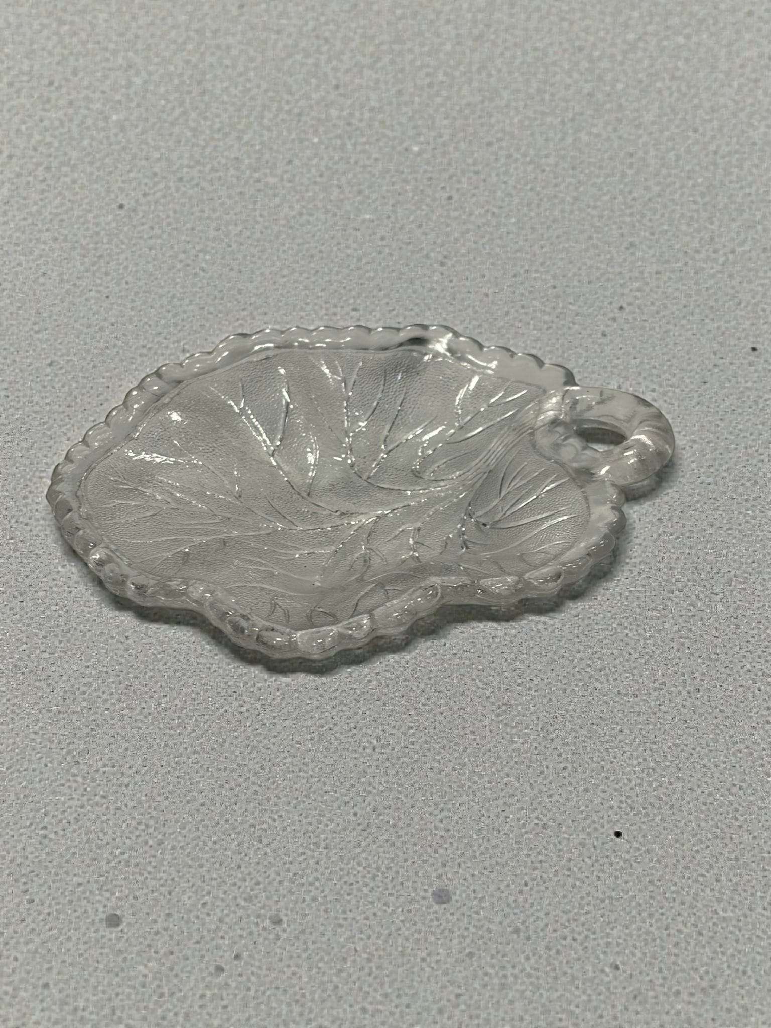 Plato de cristal con forma de hoja antigua, con asa y relieve vegetal, ideal para decoración vintage en el hogar.