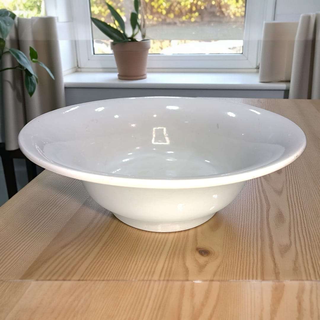 Lavabo de loza Pickman Sevilla antiguo con acabado blanco brillante, colocado sobre mesa de madera, ideal para decoración de baños históricos.