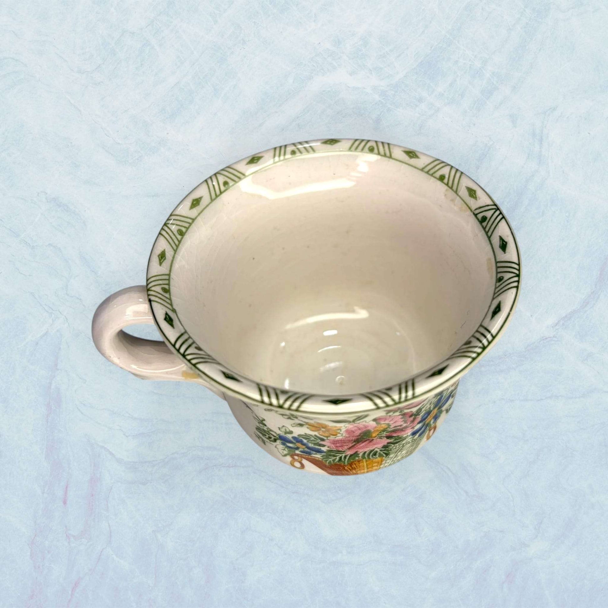 Taza de loza antigua de Cartuja con borde decorado en verde y diseño floral. Pieza del resto de Cartuja antiguo con tazas y bandeja original.