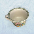 Taza de loza antigua Cartuja con borde decorado en verde y diseño floral. Pieza de colección ideal para decoración vintage en hogar o jardín.
