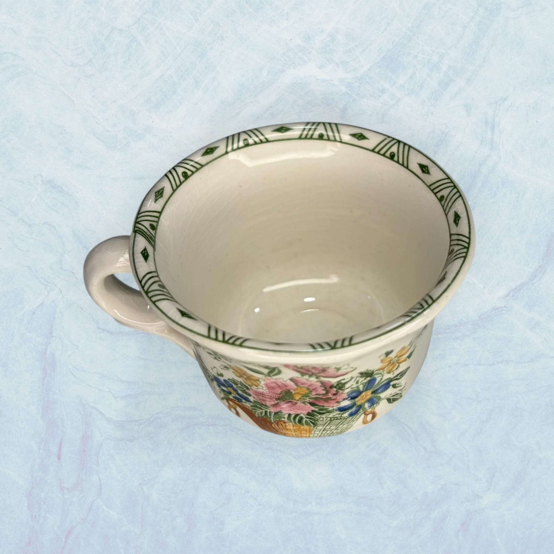 Taza de loza antigua Cartuja con borde decorado en verde y diseño floral. Pieza de colección ideal para decoración vintage en hogar o jardín.