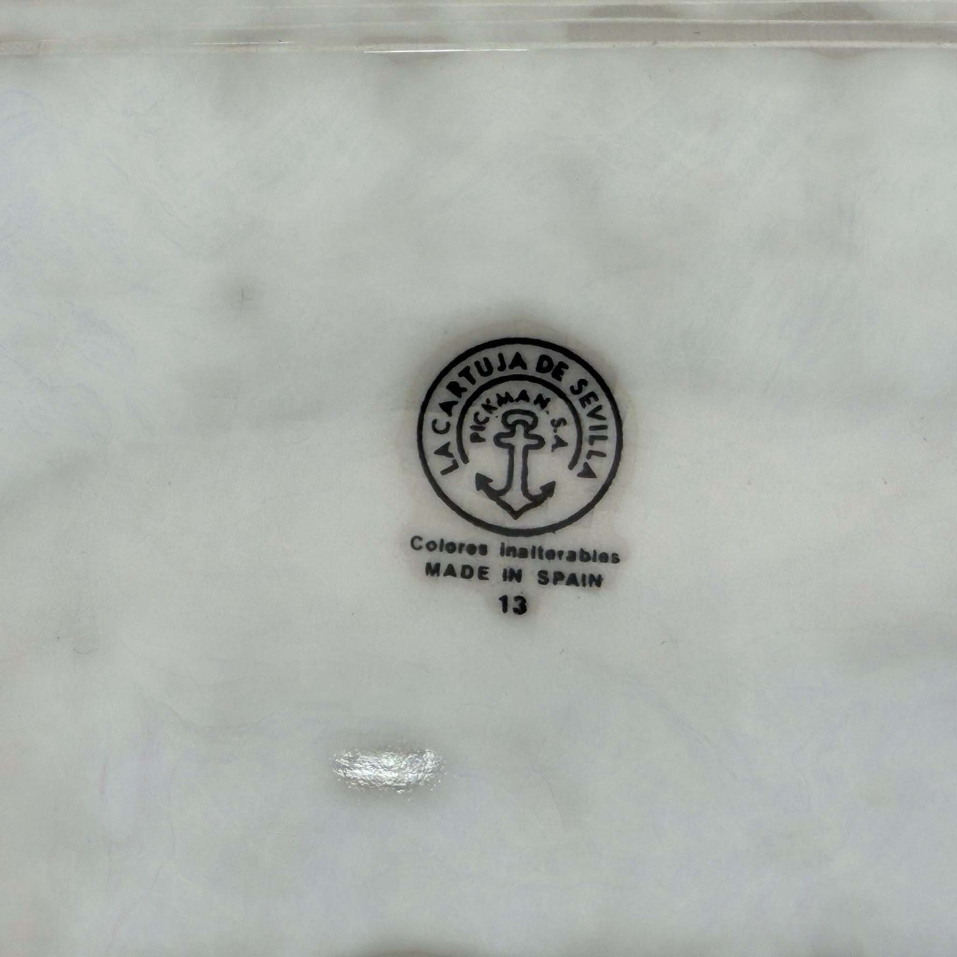 Sello original de La Cartuja de Sevilla en loza antigua, con ancla y texto 'Colores inalterables Made in Spain'. Ideal para decoración vintage.