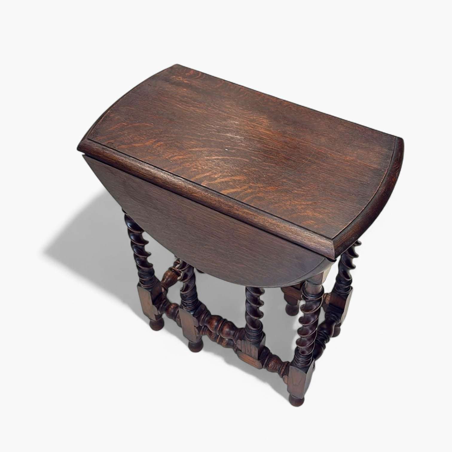 Mesa de alas antigua plegada vista desde arriba, con acabado en madera oscura y diseño ornamental de columnas salomónicas.