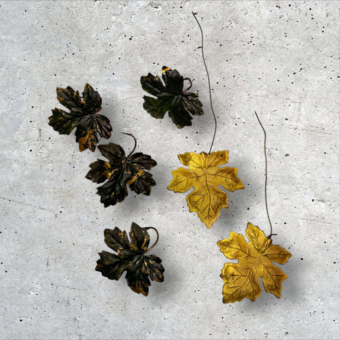 Conjunto de hojas decorativas de metal vintage doradas y verdes con acabado envejecido sobre fondo gris. Ideal para decoración artística del hogar.
