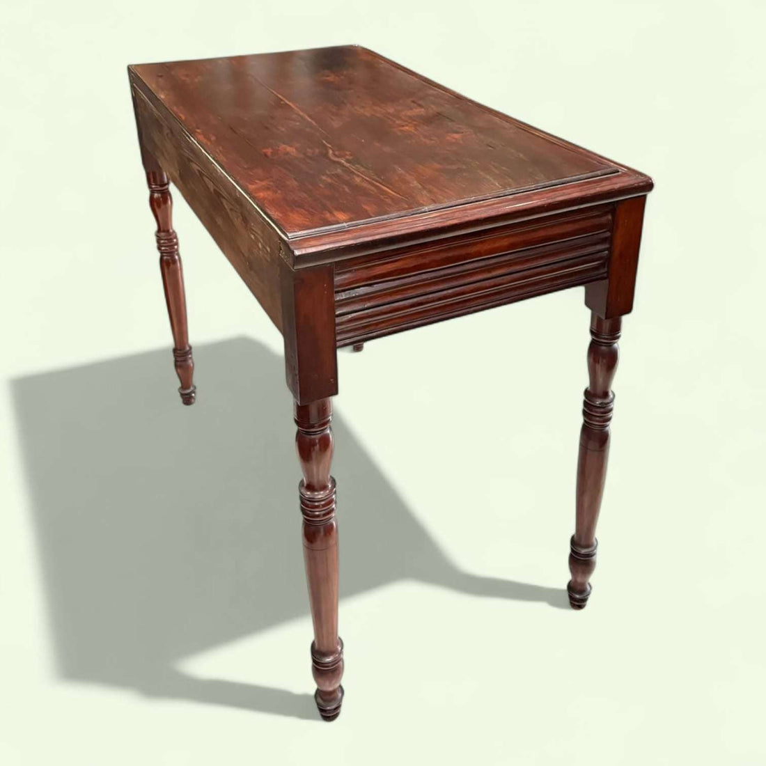 Mesa consola de caoba tallada antigua con cajón única, con detalles ornamentales en el faldón y patas torneadas, ideal para decoración clásica.