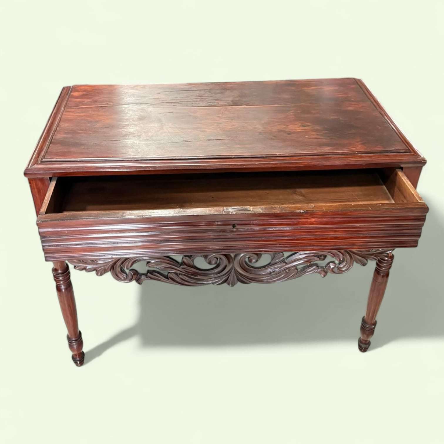 Mesa consola de caoba tallada antigua con cajón única, con el cajón abierto mostrando su funcionalidad y detalles tallados en el frente.