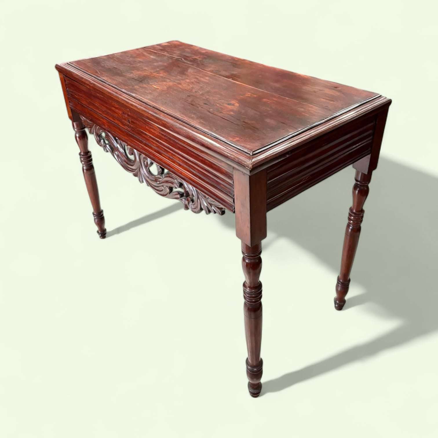 Mesa consola de caoba tallada antigua con cajón única, vista diagonal que resalta su estructura robusta y diseño artesanal en madera.