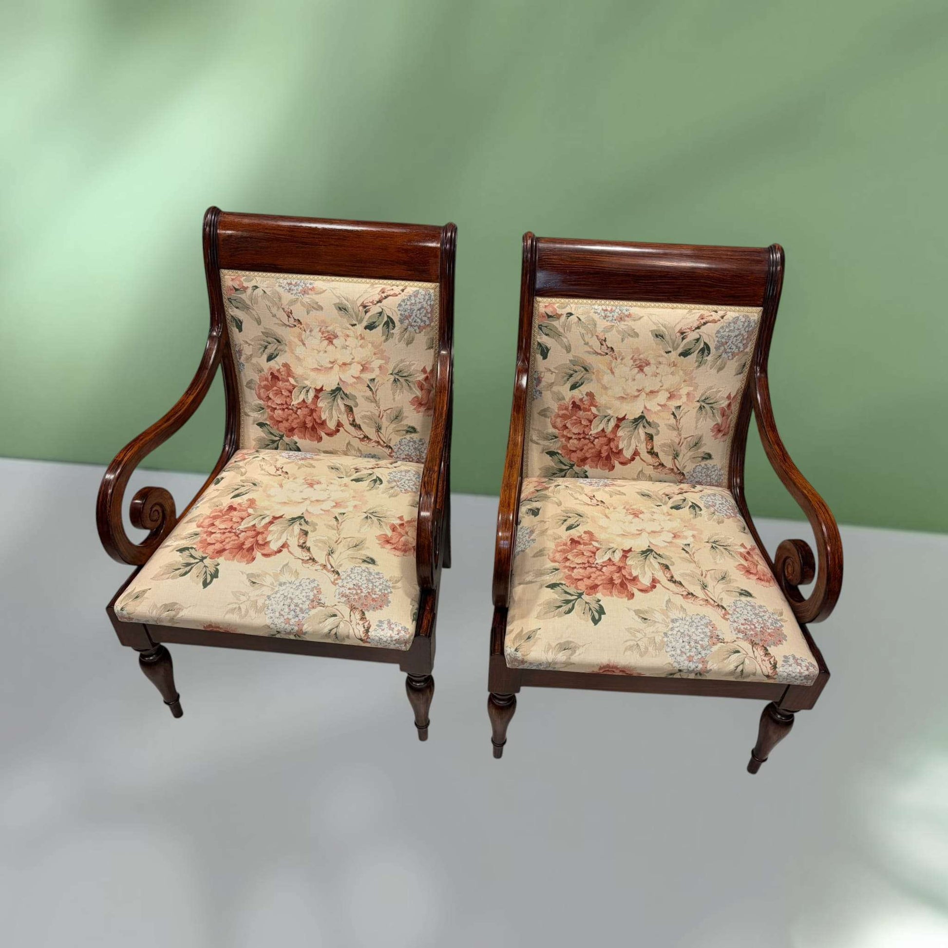 Pareja de sillones de madera con brazos clásicos y tapizado floral único, ideales para decoración elegante en interiores vintage.