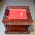Mesa expositora de caoba con cristal biselado - Vintage, con cajón tapizado en rojo y detalles dorados. Ideal para decoración clásica en el hogar.
