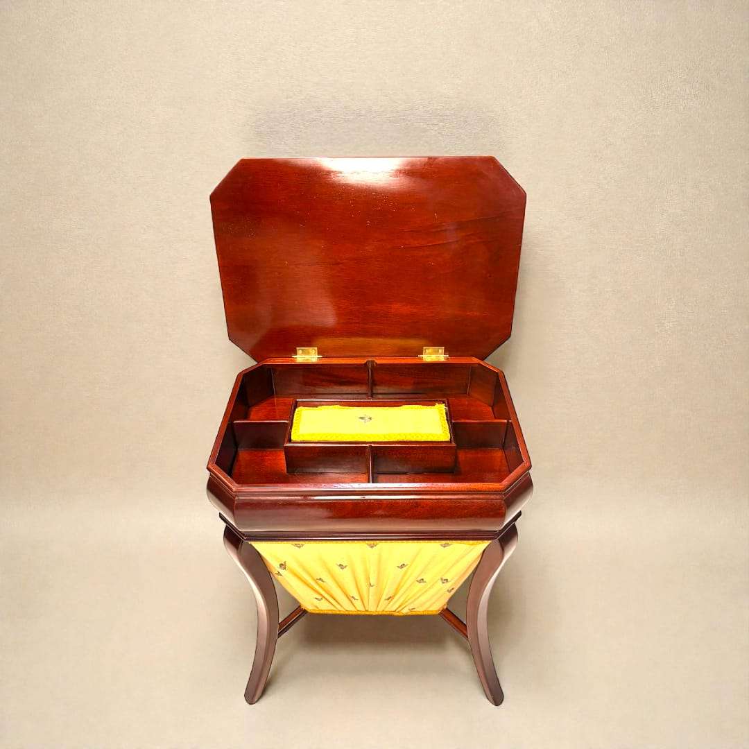 Costurero de caoba clásico con compartimentos abiertos, tapa abatible y detalles en amarillo. Ideal para decoración vintage en el hogar.
