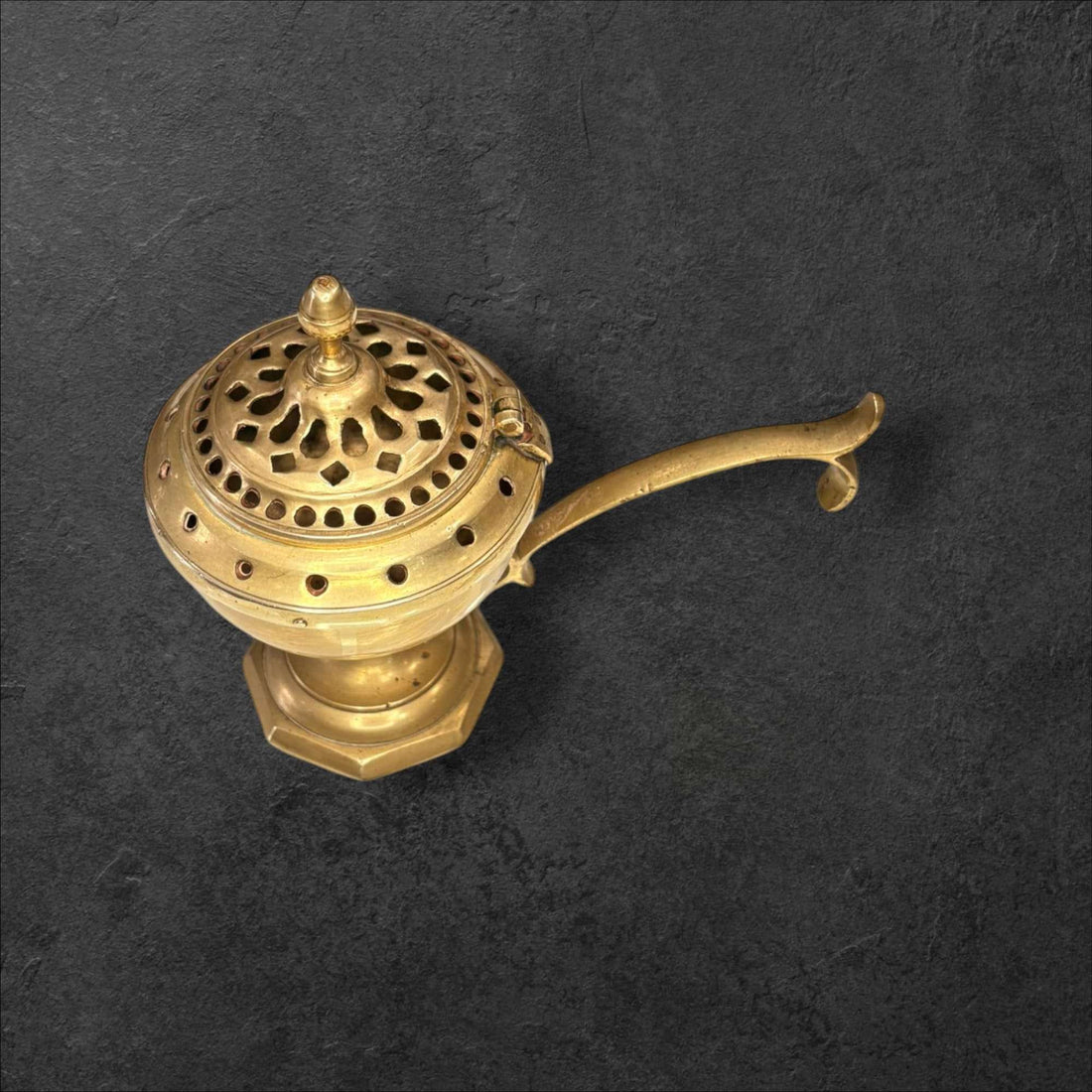 Este Incensario de metal dorado es una pieza antigua de gran atractivo visual, concebida originalmente para quemar incienso de forma controlada gracias a su recipiente interior y a su tapa perforada, que permite la salida del aroma y del humo. 