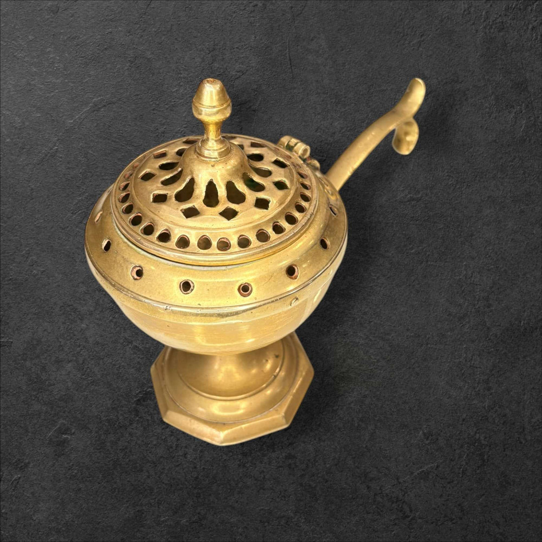 Este Incensario de metal dorado es una pieza antigua de gran atractivo visual, concebida originalmente para quemar incienso de forma controlada gracias a su recipiente interior y a su tapa perforada, que permite la salida del aroma y del humo. 