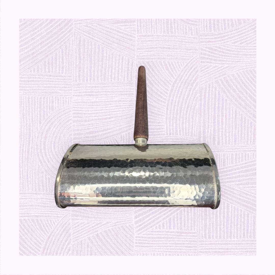 Este recoge migas de metal plateado con mango de madera es una pieza antigua de mesa creada originalmente para retirar discretamente las migas del mantel entre servicios, manteniendo la presentación limpia y cuidada. 