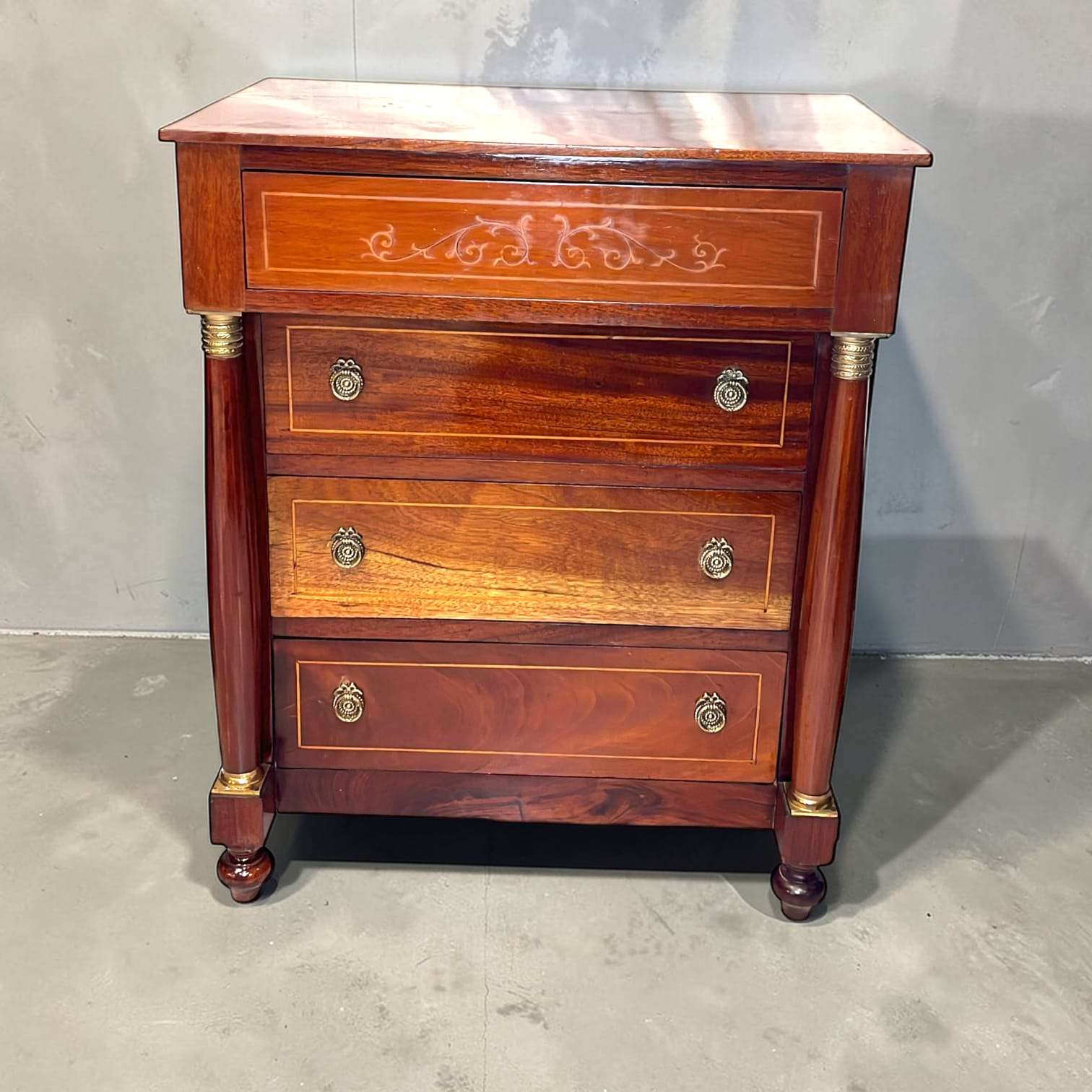 El cajón superior incorpora una decoración lineal ornamental, mientras los inferiores presentan tiradores metálicos circulares que refuerzan su estética histórica.