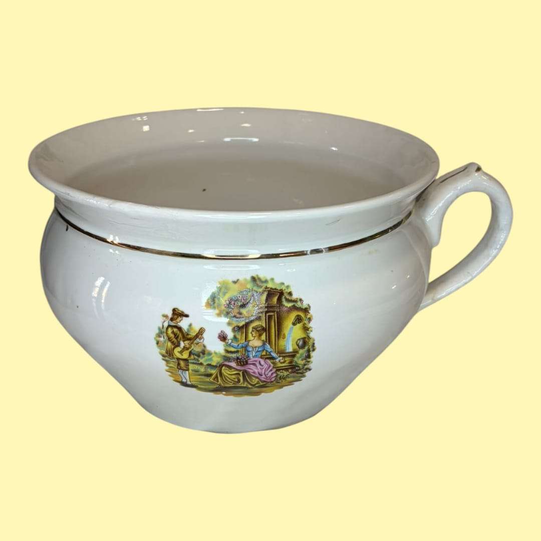 Su silueta bulbosa, la boca ancha de perfil abierto, el asa curva de buen tamaño, la cenefa dorada perimetral y la escena estampada de aire romántico son rasgos que lo dif