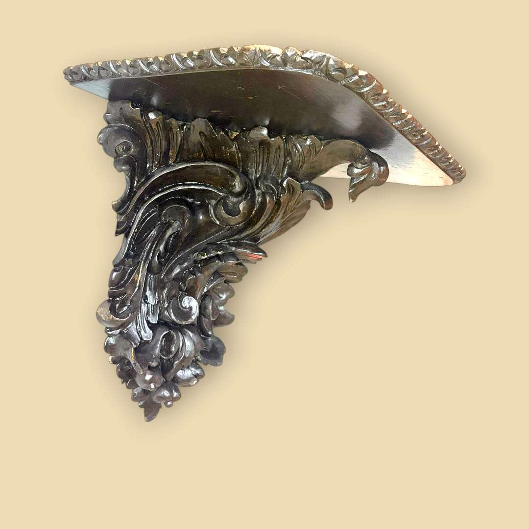 La zona inferior muestra una talla muy expresiva, con volutas, hojas y motivos vegetales que recuerdan el lenguaje decorativo del gusto gótico reinterpretado en madera.