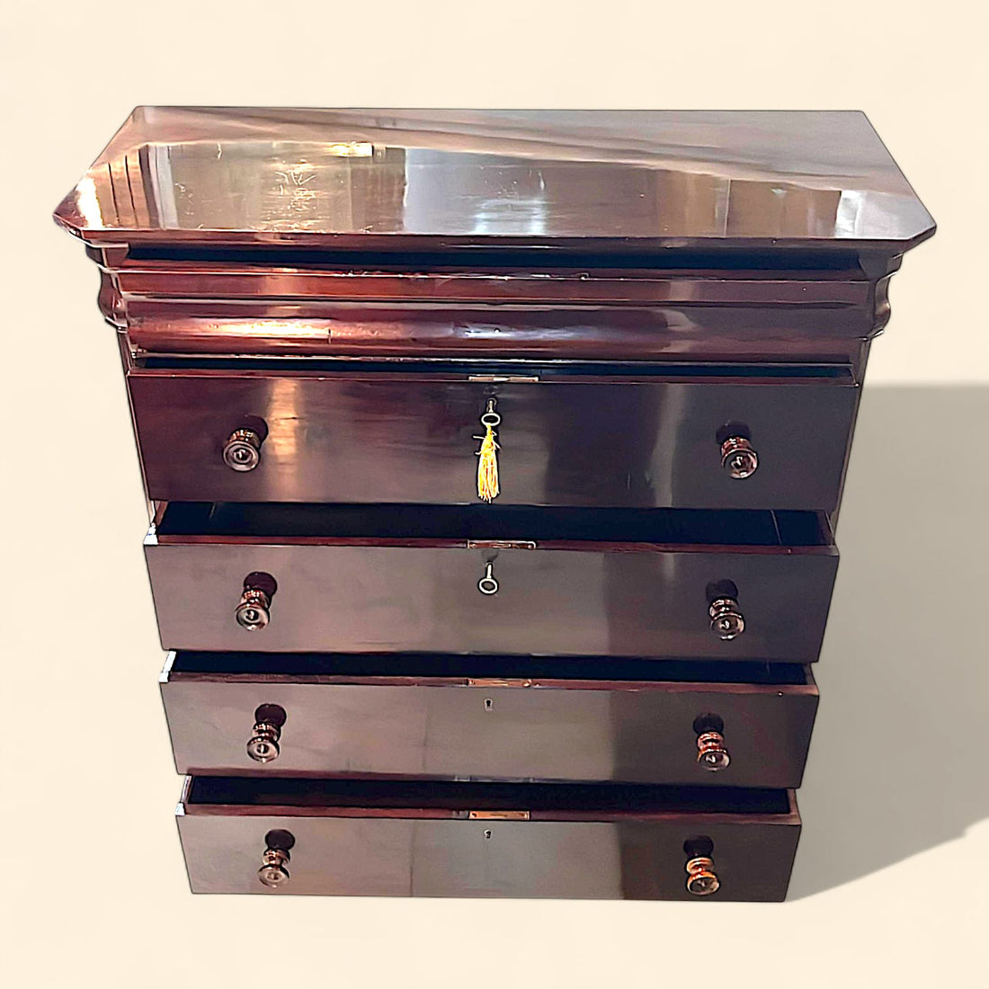 Cómoda antigua de caoba en perspectiva lateral izquierda, mostrando la amplitud de la tapa superior y la veta natural de la madera en el costado.