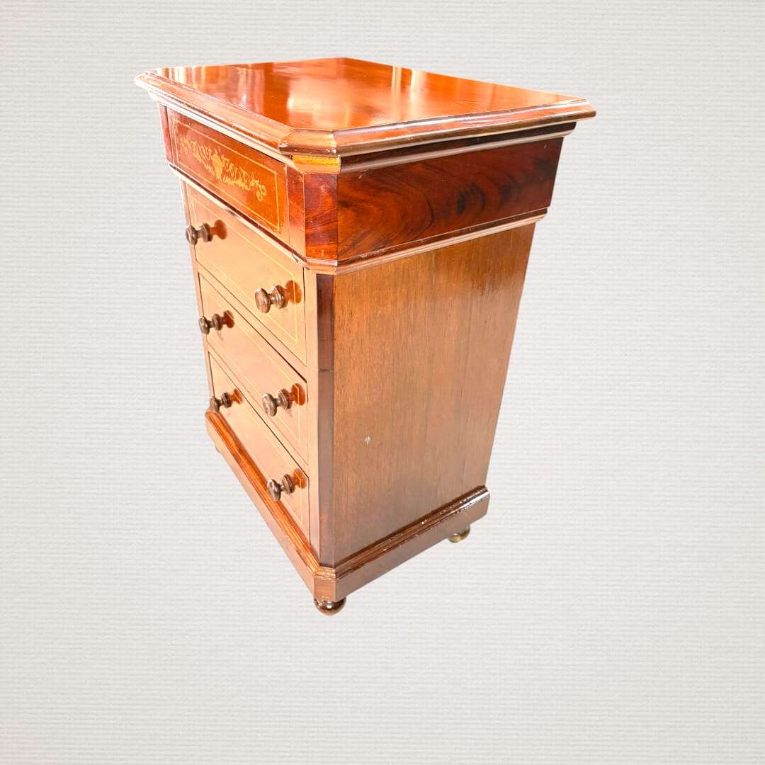 En las imágenes se aprecia una estética muy cuidada, con frente recto, pequeños pomos torneados, patas redondeadas y una tapa superior volada con esquinas achaflanadas que realza su silueta. 