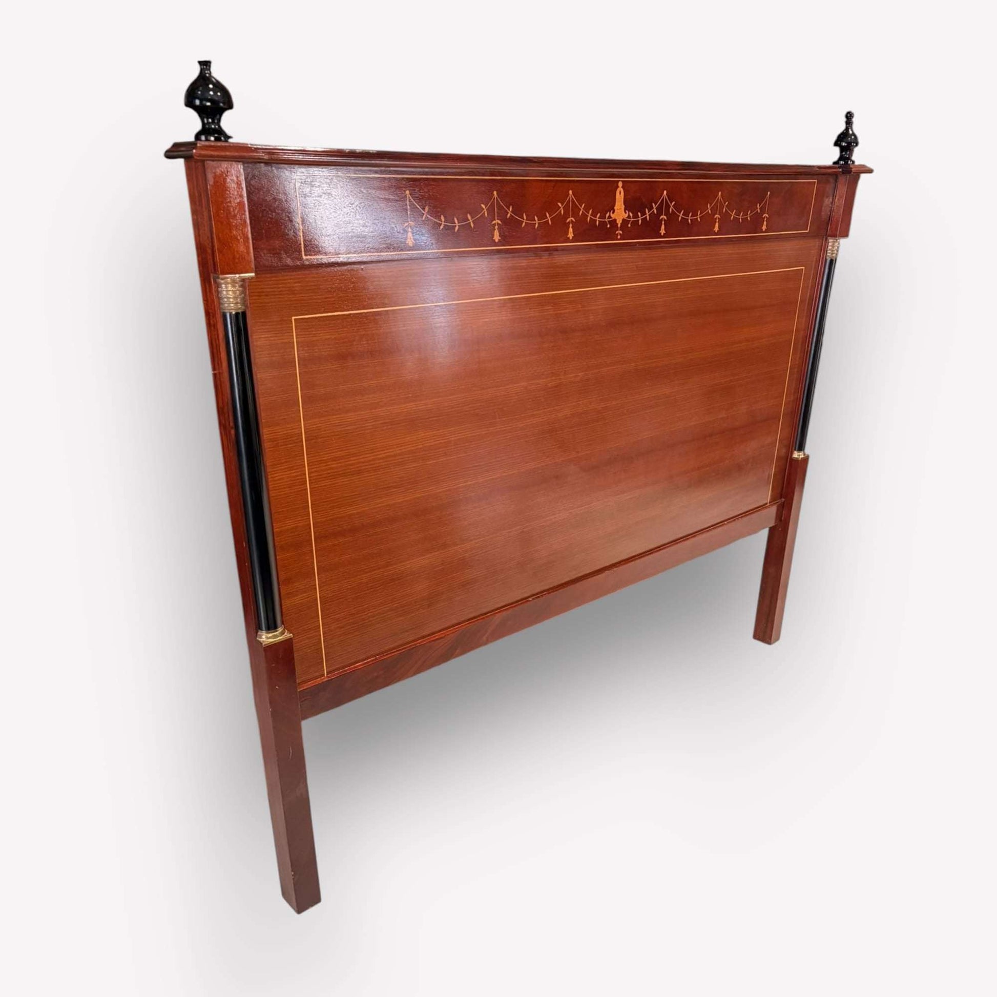 En la parte superior luce una franja decorada con fina marquetería lineal y motivo central ornamental, de inspiración clásica, que refuerza su carácter distinguido. El remate sup