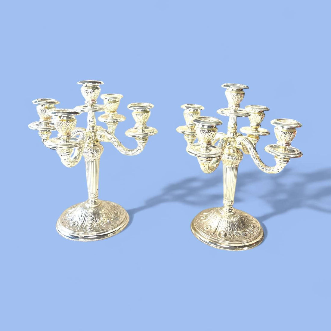 Con medidas de 19,5 x 19,5 x H27,5 cm cada uno, estos Candelabros presentan una composición de cinco luces, con un brazo central elevado y cuatro brazos curvos laterales de gran equilibrio ornamental. 