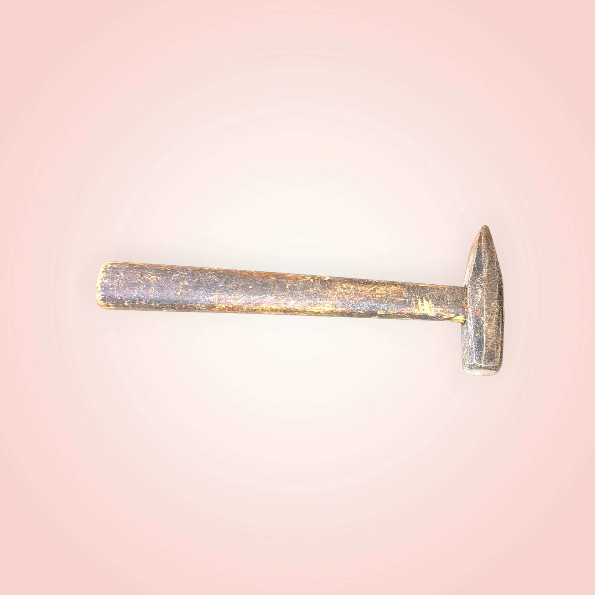 Se aprecia un cabezal de metal de líneas rectas, con una zona de golpeo compacta y una parte opuesta afilada, característica de herramientas tradicionales de oficio. 