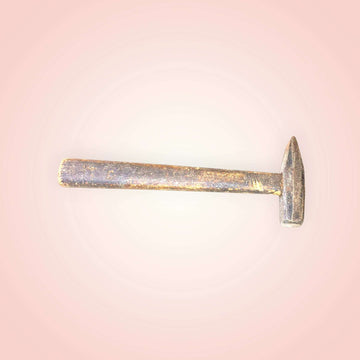 Se aprecia un cabezal de metal de líneas rectas, con una zona de golpeo compacta y una parte opuesta afilada, característica de herramientas tradicionales de oficio. 