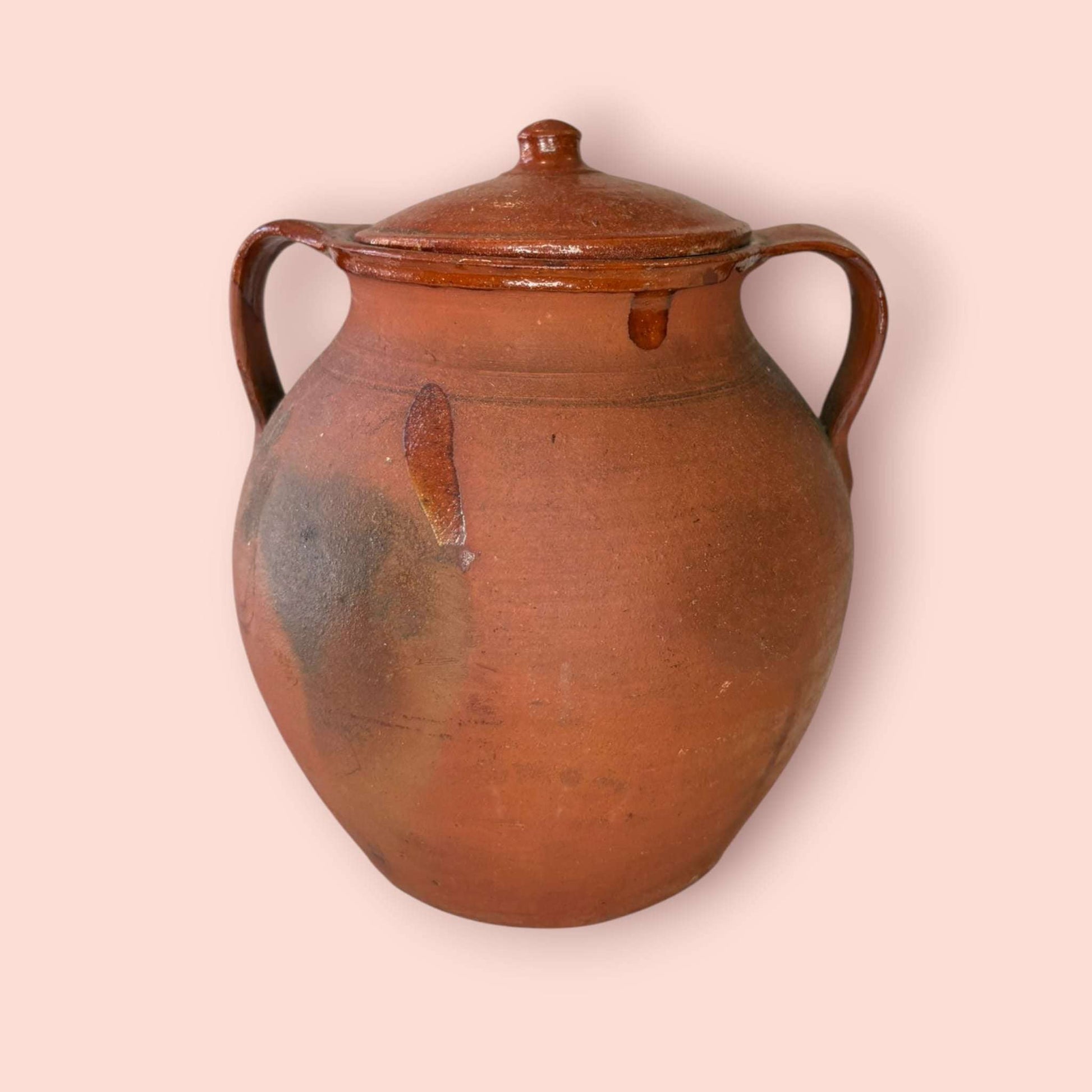 Esta Orza antigua de barro cocido es una pieza de fuerte carácter tradicional, pensada originalmente para conservar alimentos y mantener su contenido protegido gracias a su tapa y a la naturaleza del barro.