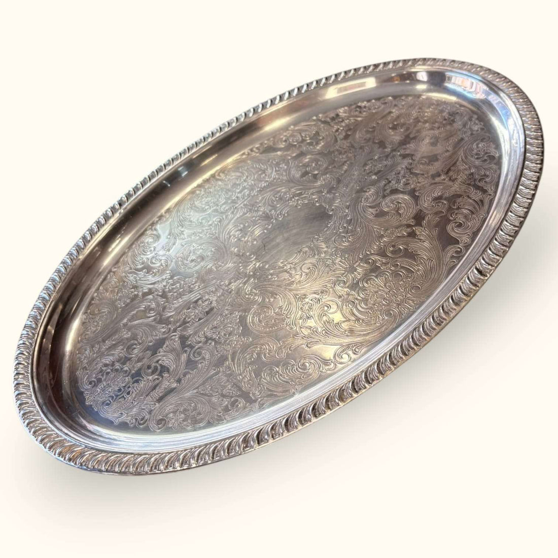 Bandeja antigua de metal plateado con relieves decorativos y borde elevado, pieza vintage para decoración y servicio.