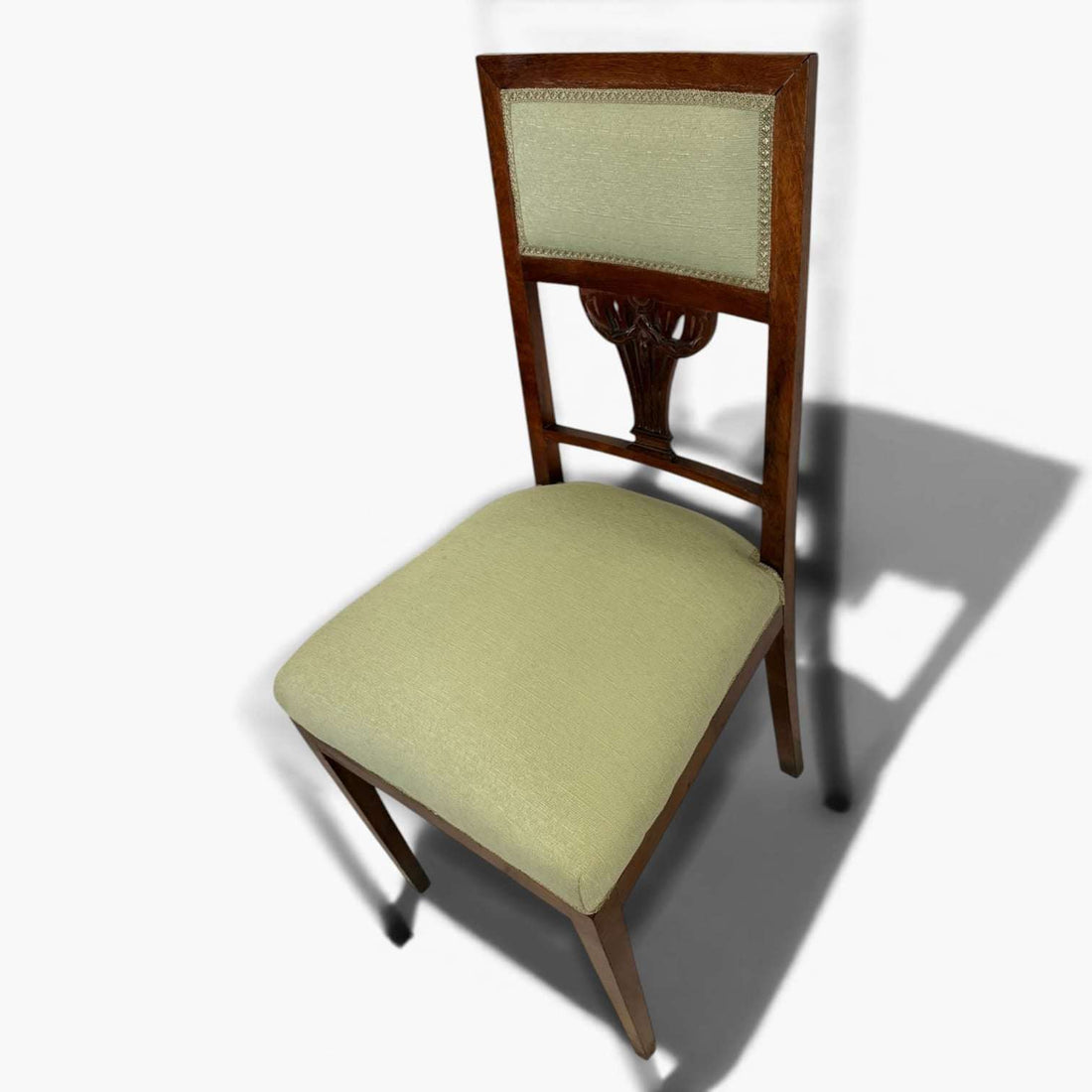 El tapizado verde tanto en el asiento como en el respaldo aporta confort visual y un atractivo contraste con la madera de tono cálido.