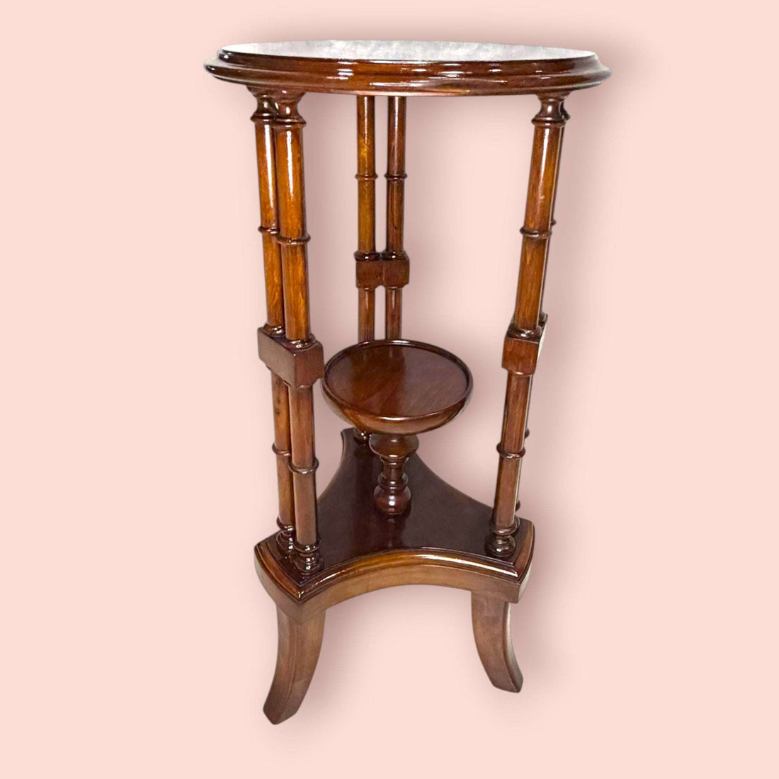 Estos Veladores destacan por una estructura muy original: tablero superior circular, columnas verticales decorativas y una pequeña repisa central que permite crear dos alturas de exposición. Esta repisa resulta perfecta para colocar una maceta con flores, una figura pequeña, una porcelana, una vela decorativa o un detalle especial, mientras que la parte superior puede utilizarse para una lámpara, un jarrón o una pieza protagonista.

En las imágenes se aprecia un acabado brillante de tono caoba cálido, con t